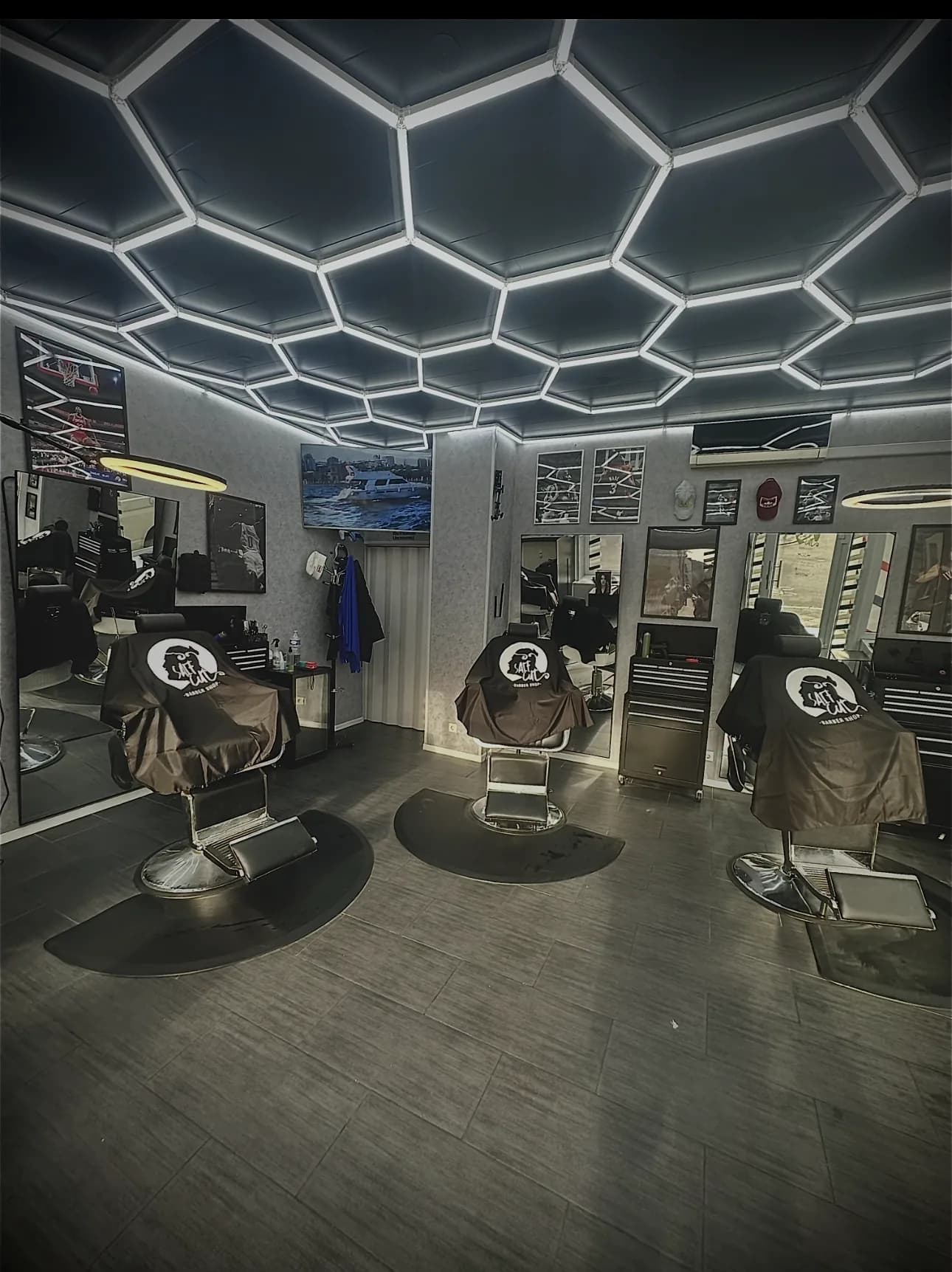 Weitwinkel: drei Barberstühle unter der weiß leuchtenden Hexagon-LED-Decke
